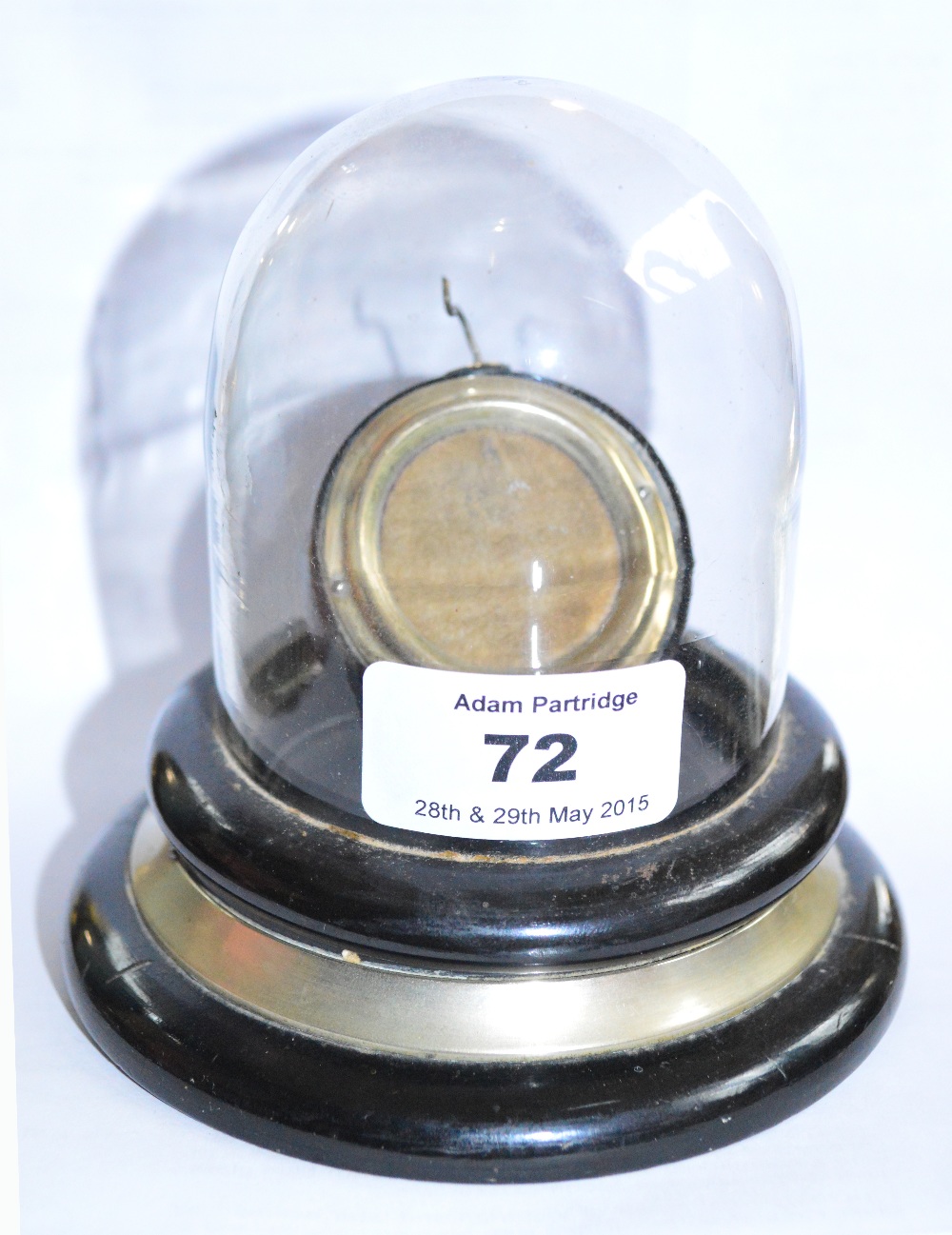 A pocket watch stand under a hinged glass dome on ebonised socle base, height 11cm.