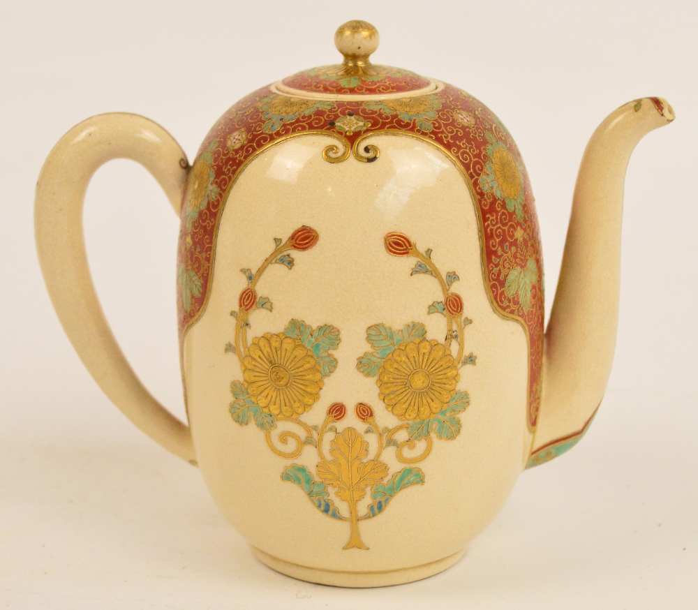 A Japanese Meiji period Satsuma teapot, the angled spout above floral decorated red and cream ground