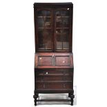 An early 20th century oak bureau bookcase on ring turned supports, glazed double doors, width 75cm.