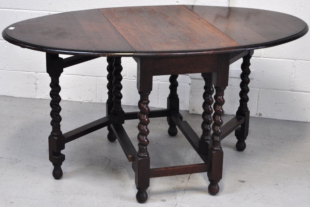 An oak drop leaf table on barley twist supports with cross stretchers.