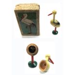 A boxed small vintage wooden toy stork with a tiny man inside.