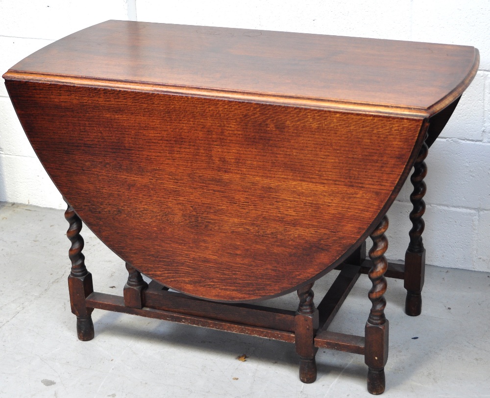 An early 20th century oak drop leaf table on barley twist supports,