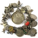 A silver bracelet with approximately sixty silver and white metal charms to include Victorian coins