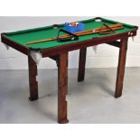 A table top pool table of small proportions with four cues,