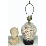 A glass baluster form table lamp filled with various shells,