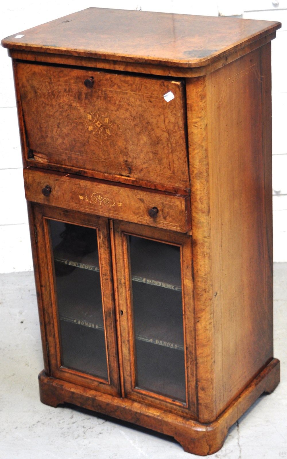 A 19th century walnut writing bureau above glazed music cabinet with central drawer and inlaid