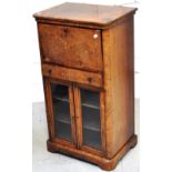 A 19th century walnut writing bureau above glazed music cabinet with central drawer and inlaid