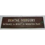 A copper sign, "Dental Surgery, Entrance 1st. Right In Woolton Park".