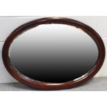 An early 20th century oval mahogany framed wall mirror with bevelled edge, width 84cm.