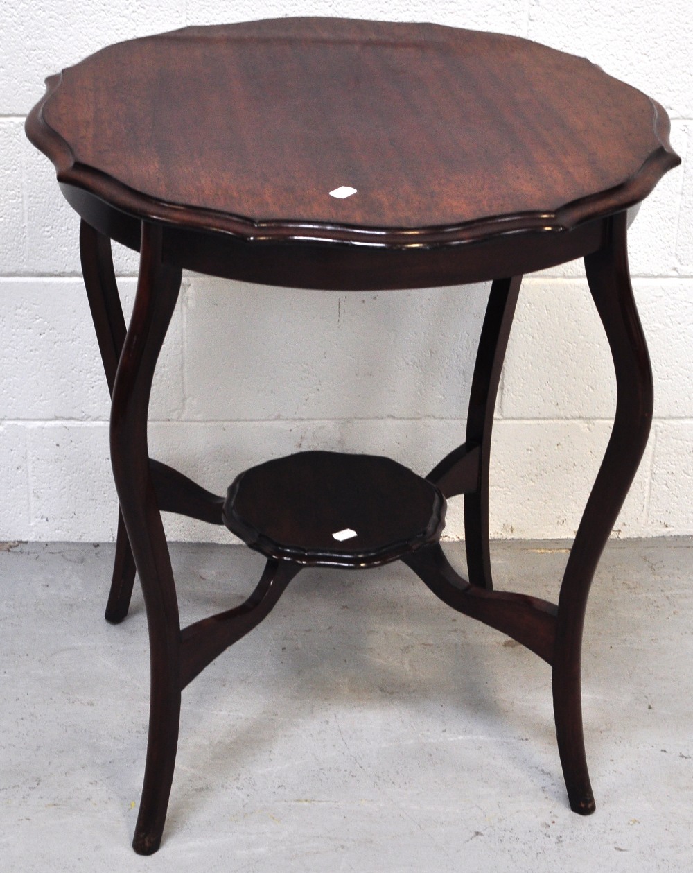 An early 20th century shaped side table on cabriole legs, with lower smaller shaped shelf,