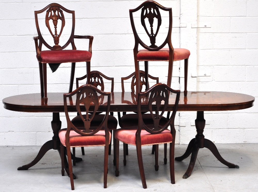 A reproduction mahogany extending dining table on two tripod supports with single extending leaf,