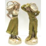 A pair of early 20th century Royal Dux figures of a young lady and young man both carrying baskets,