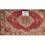 A red ground Kum carpet, the central motif of flowers and sprays surrounded by a rectangular border,