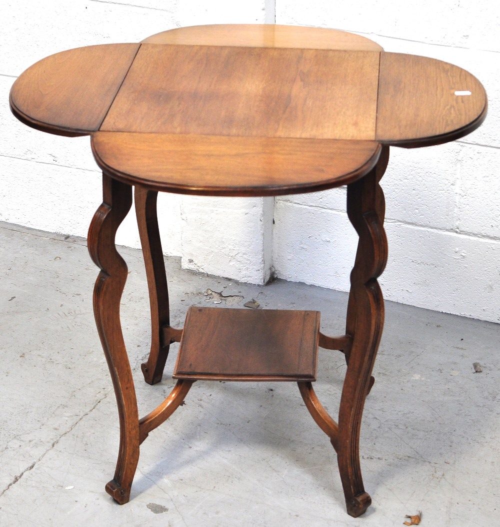 A 20th century oak drop leaf occasional table with lower shelf and raised on incised outswept