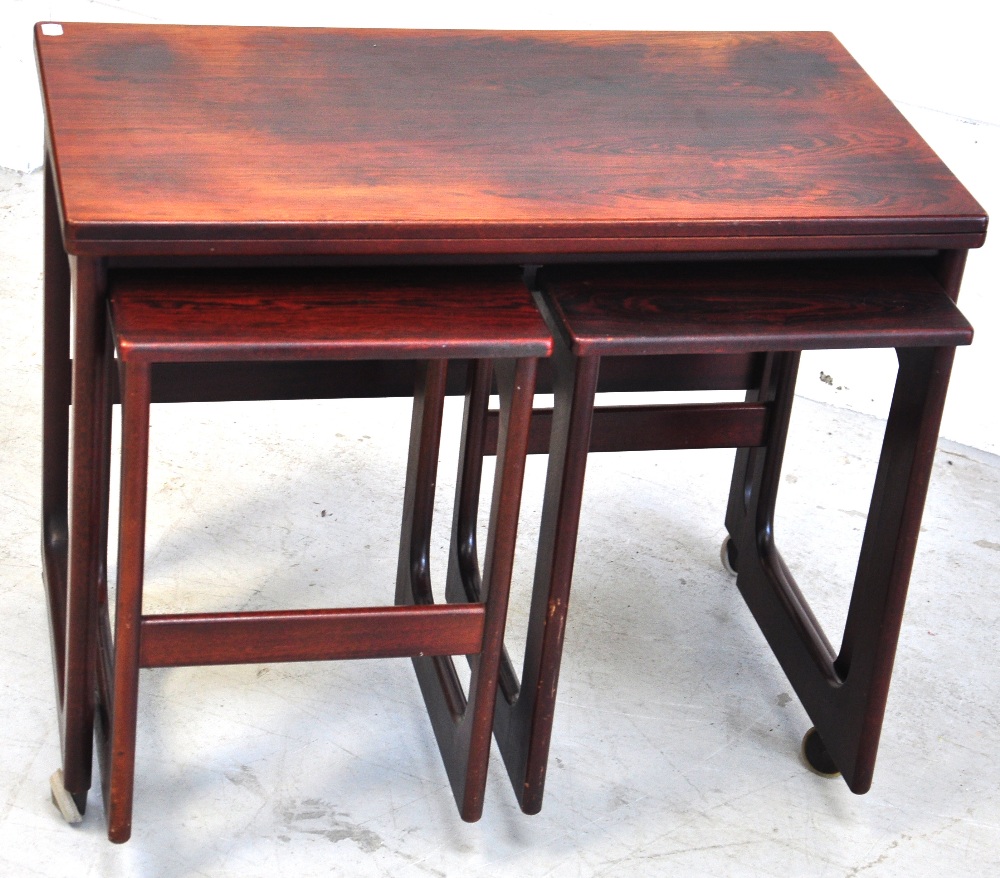 A nest of three 1960s rosewood tables, largest on wheels, width 74cm.