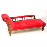 A late Victorian burgundy upholstered chaise longue raised on ring turned legs.