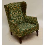 An Edwardian wingback armchair raised on turned supports.