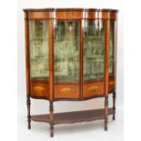 An exhibition quality Edwardian satinwood mahogany and inlaid display cabinet of serpentine outline,