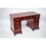 A reproduction mahogany nine drawer pedestal desk with leather lined gilt tooled writing surface,