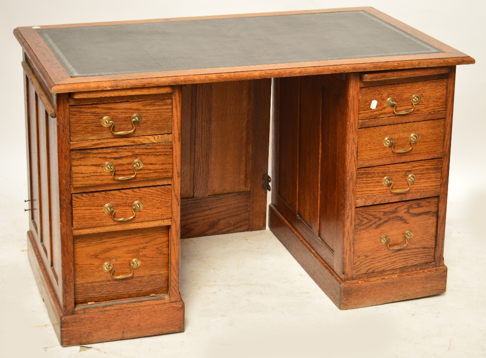 A mid 20th century oak pedestal desk of plain design with three shallow drawers and one deep drawer