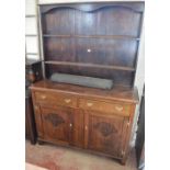 An Edwardian oak dresser with boarded plate rack above two frieze drawers and pair of carved