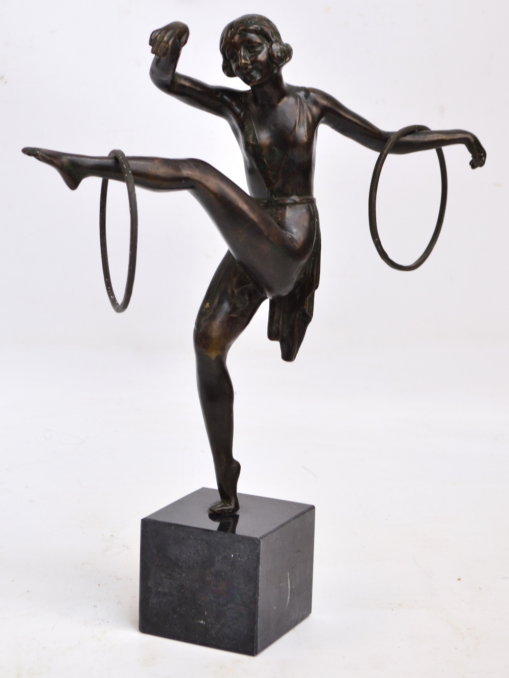 An Art Deco style spelter figure of a gymnast dancing with hoops balancing on one leg,