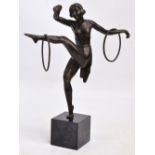 An Art Deco style spelter figure of a gymnast dancing with hoops balancing on one leg,