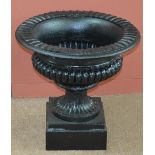 A large cast iron garden urn of squat campana form on circular socle to a square base, height 52cm,