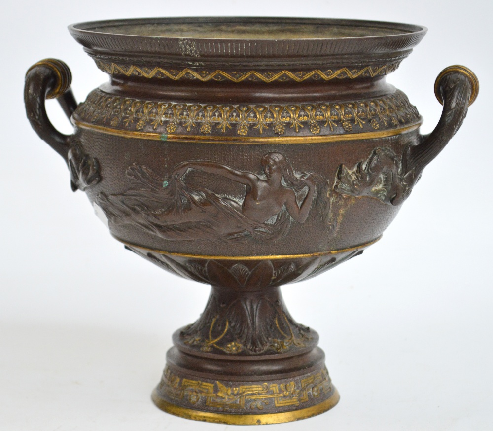 A bronze twin handled urn decorated with classical recumbent scantily clad female figures,