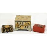 A Japanese lacquer miniature chest of drawers with two small and one long drawer decorated with
