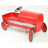 A mid 20th century red pedal car with rubber edged wheels, and go-faster white metal stripe,