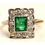 A square Art Deco emerald and diamond ring, the rectangular and emerald surrounded by fourteen small