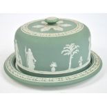 A late 19th century Wedgwood pale green jasperware cheese dome and stand decorated with classical