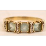 A 9ct yellow gold dress ring with three square cut aquamarines with diamond chips between,