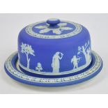 A late 19th century Wedgwood blue jasperware cheese dome and stand decorated with classical motifs