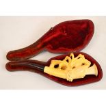 A cased Meerschaum pipe carved as a bird perched on a branch amongst leaves.