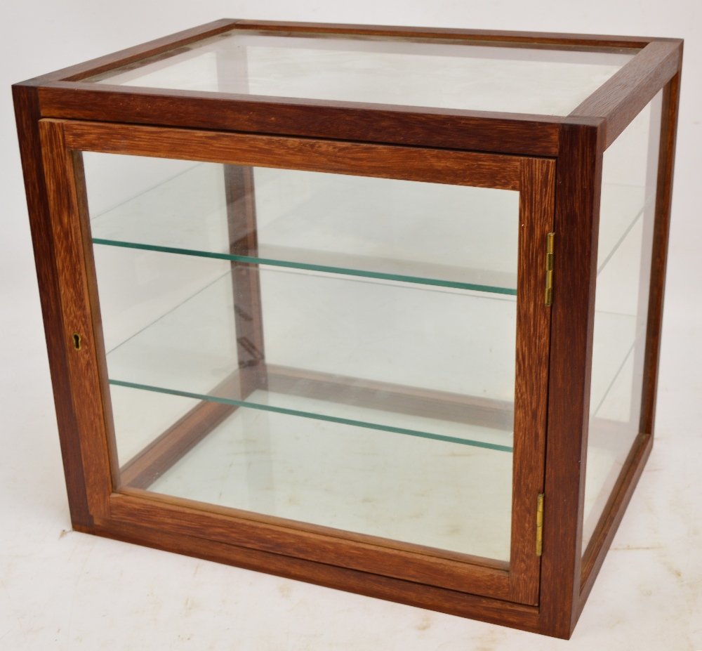 A glazed wooden framed table top display cabinet, the single door enclosing two glass shelves,