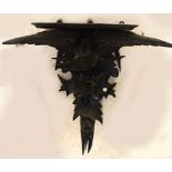 A late 19th century Black Forest type carved wooden wall bracket set with an eagle above fruit,