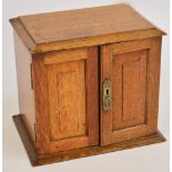 An Edwardian oak letter/writing cabinet, with doors and hinged top enclosing a letter rack, a pen