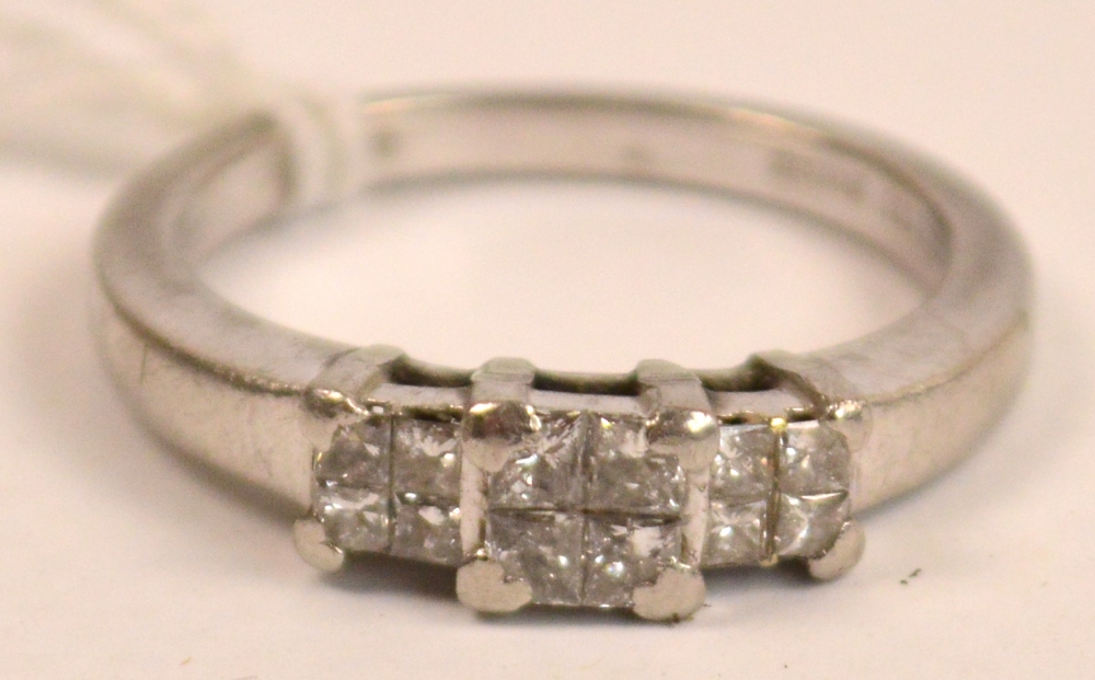 A platinum diamond set ring with three panels each set with four small diamonds, rings size O.