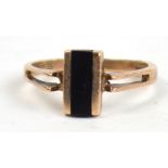 A 9ct yellow gold dress ring with single horizontal black enamel band on pierced shoulders,