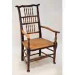 A 19th century ash and beech spindle back rush seated elbow chair with wavy top rail.