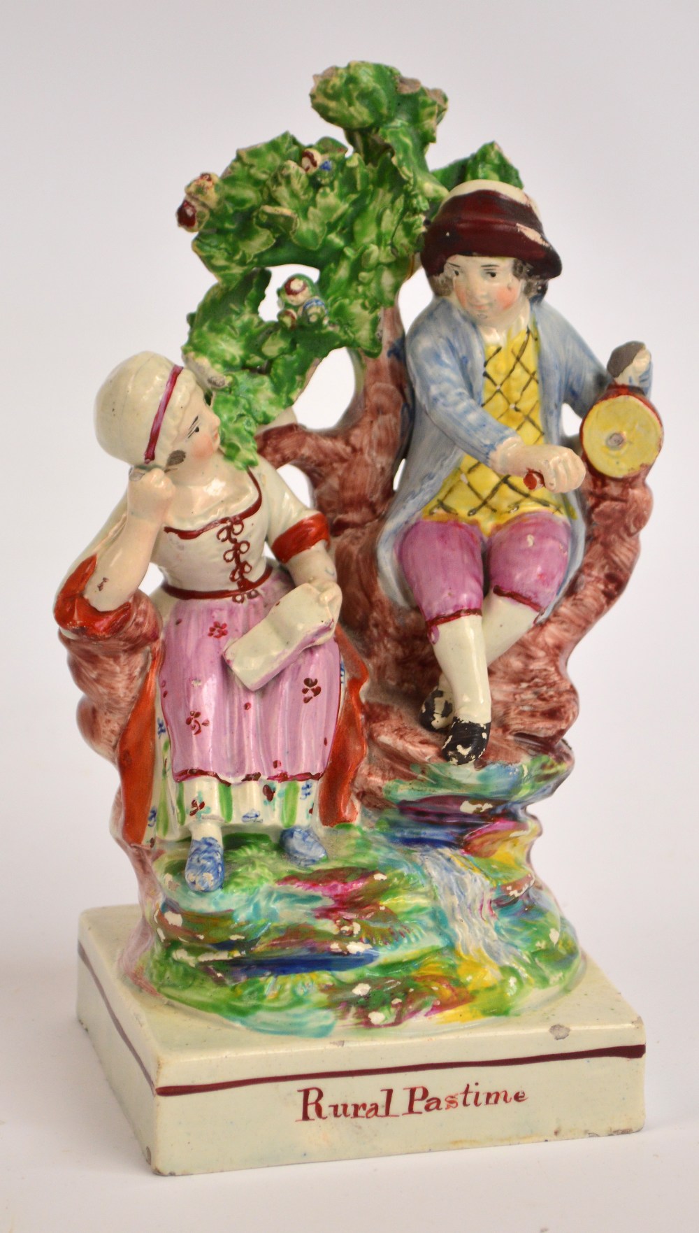 An early to mid 19th century Staffordshire figure of a girl and boy seated on a tree inscribed "