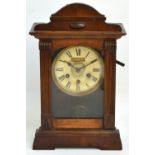 An early 20th century American walnut cased eight day alarm mantel clock with circular dial set