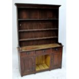 A 19th century scumbled pine dog kennel dresser, the boarded plate rack above three frieze drawers,