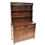 A 20th century oak Priory style dresser with boarded plate rack.