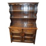 A reproduction oak dresser with boarded plate rack, width 122cm.