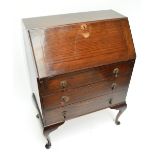 An oak three drawer bureau raised on cabriole legs.