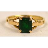 A square cut emerald ring set on a yellow gold band (mark obscured) with pierced shoulders, size