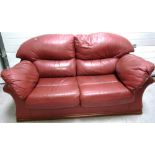 A contemporary maroon leather two seat sofa on wooden plinth base, approx width 170cm.